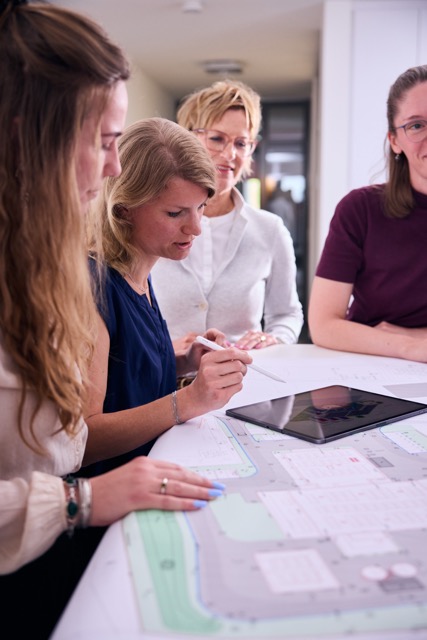 Vier KollegInnen beraten sich an einem Tisch