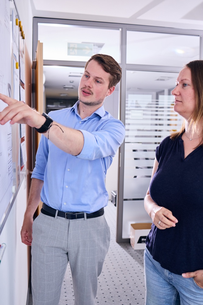 Zwei Mitarbeiter an einem Whiteboard besprechen eine Zeichnung