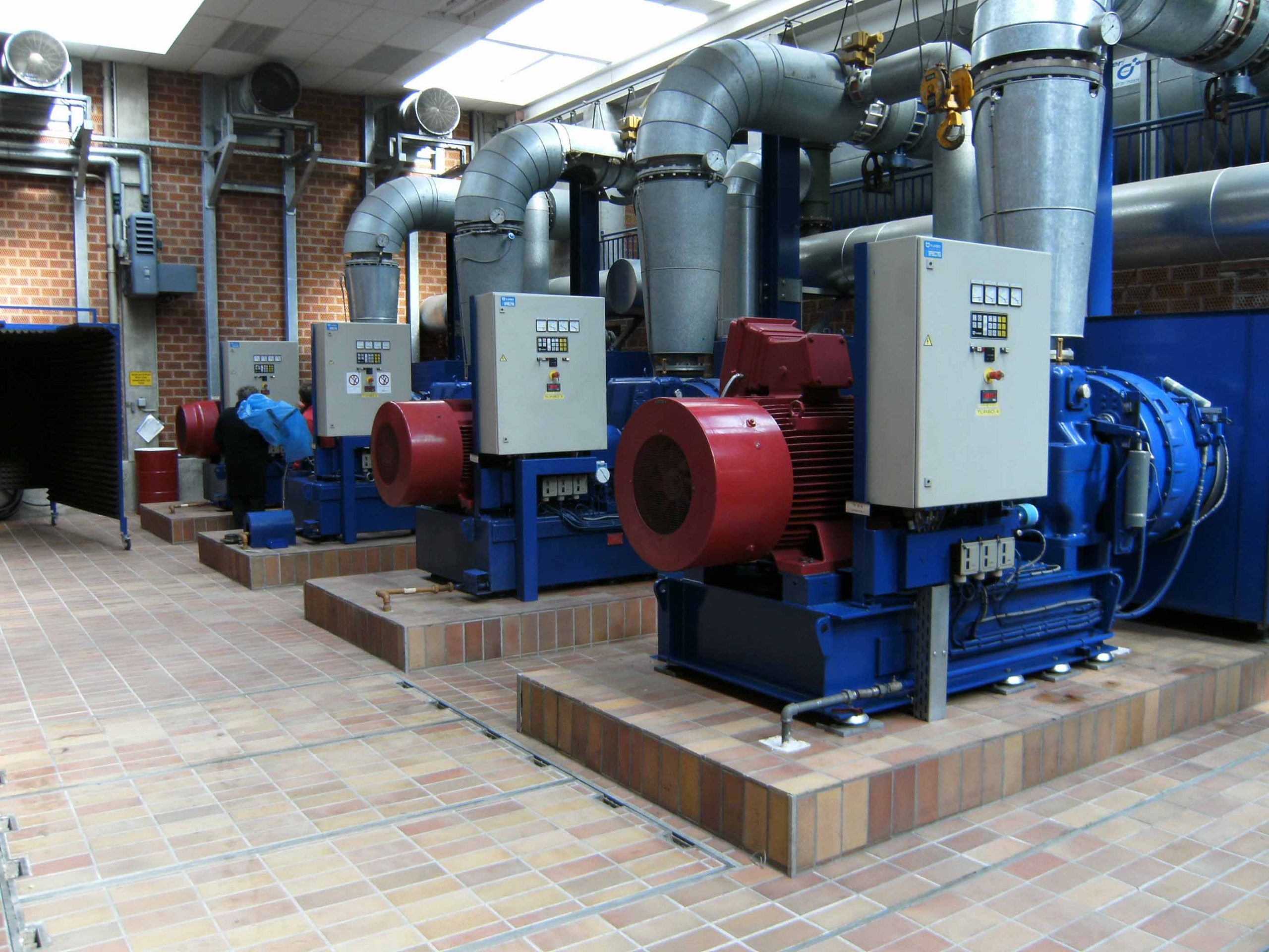 Maschinenhalle eines Klärwerks mit großen Gebläseaggregaten, Rohrleitungen und Steuerungstechnik zur Belüftung der Abwasserbehandlung