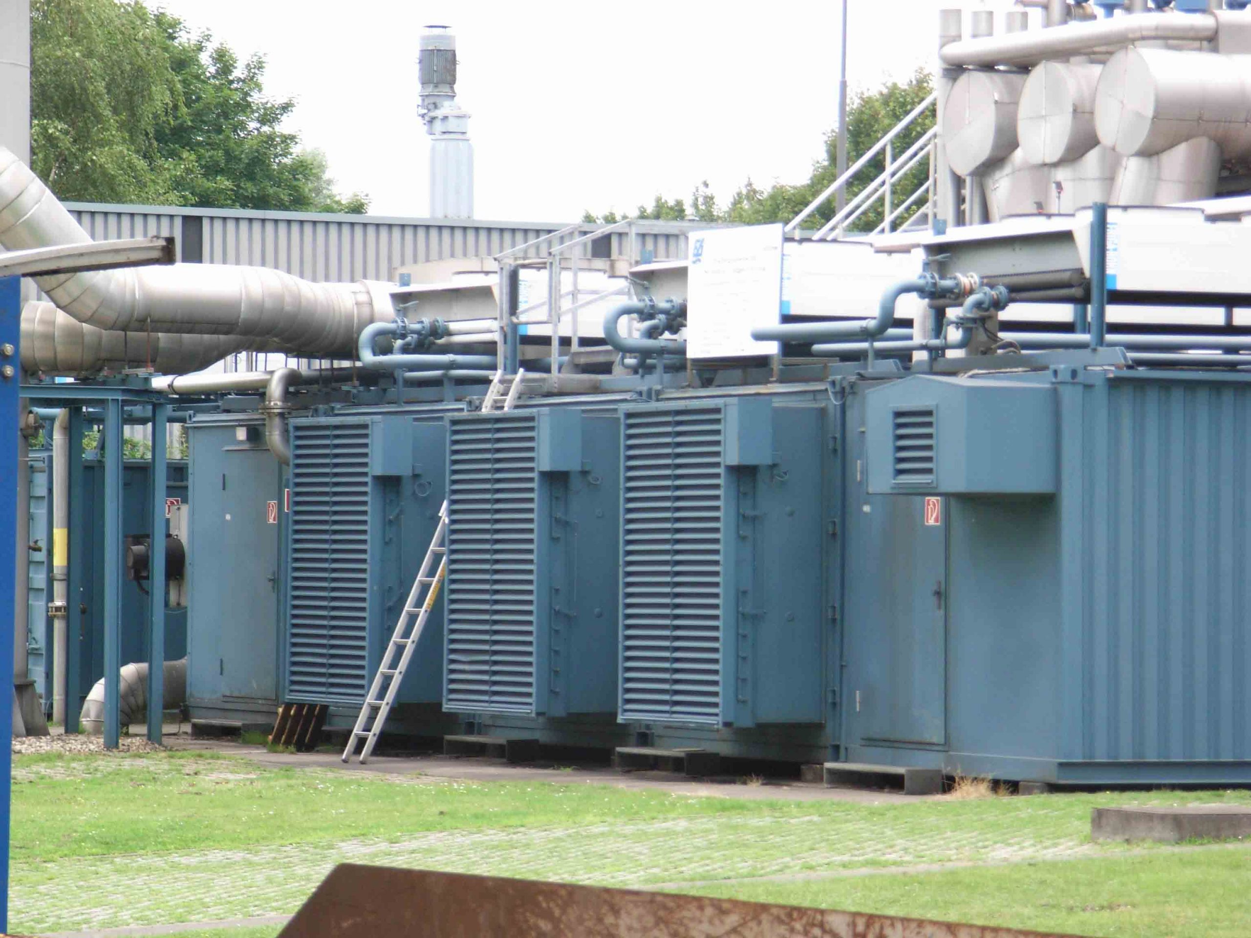 Blockheizkraftwerke einer Kläranlage mit eingehausten Motoraggregaten, Rohrleitungen und technischer Infrastruktur im Außenbereich