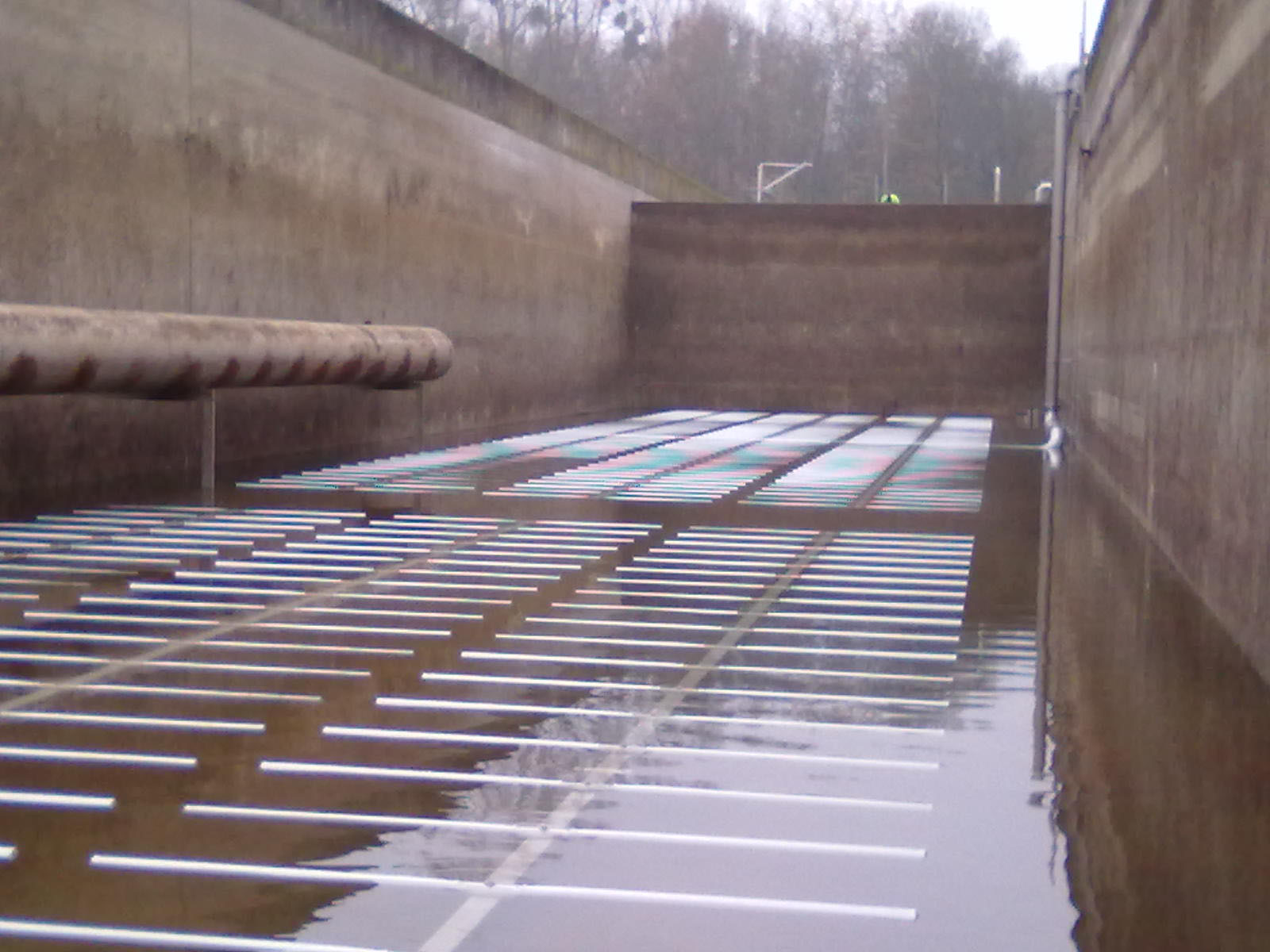 Belebungsbecken einer Kläranlage mit feinblasigem Belüftungssystem und parallel angeordneten Rohrleitungen im Betonbecken