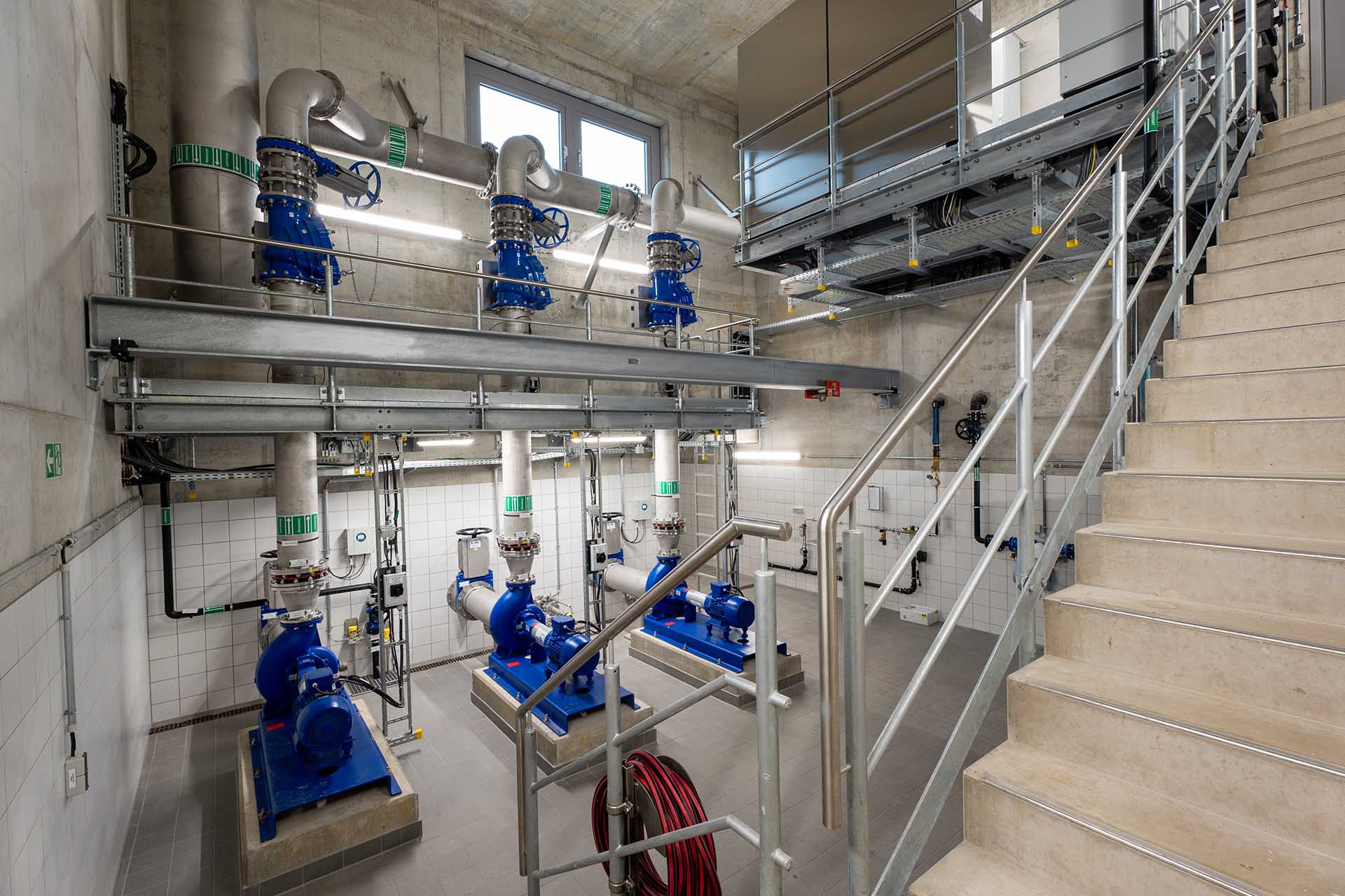 Innenraum eines Pumpwerks mit mehreren Kreiselpumpen, Rohrleitungen und Treppenanlage