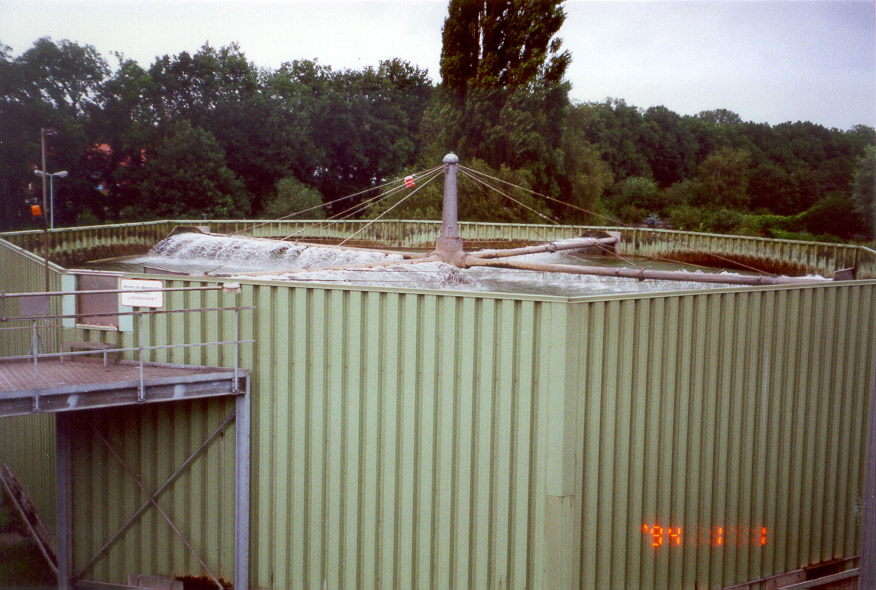 Kläranlagenbecken mit rotierendem Räumwerk und schaumigem Wasser von oben gesehen