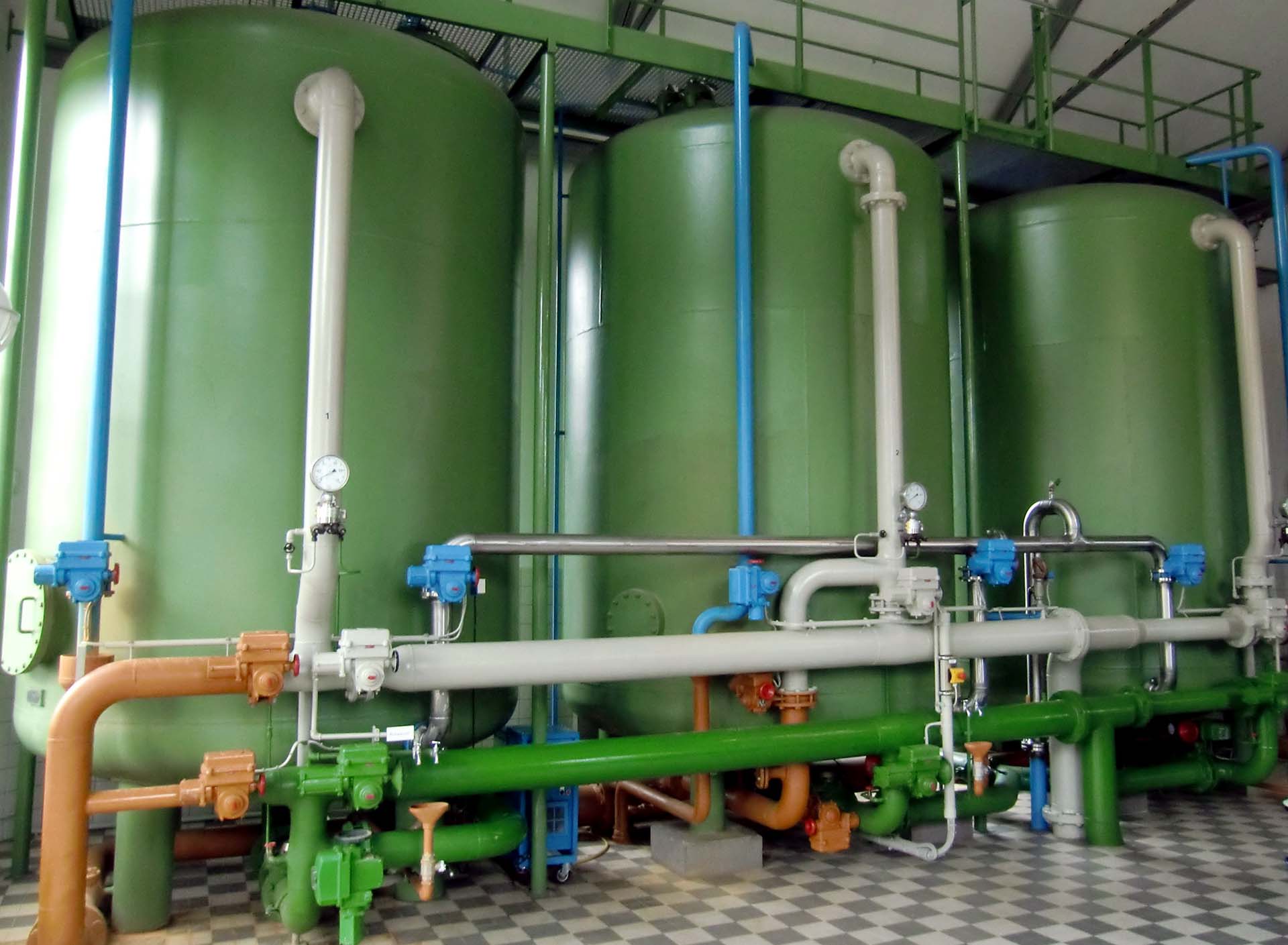 Mehrere große Filterbehälter mit Rohrleitungen und Armaturen in einer Trinkwasseraufbereitungsanlage